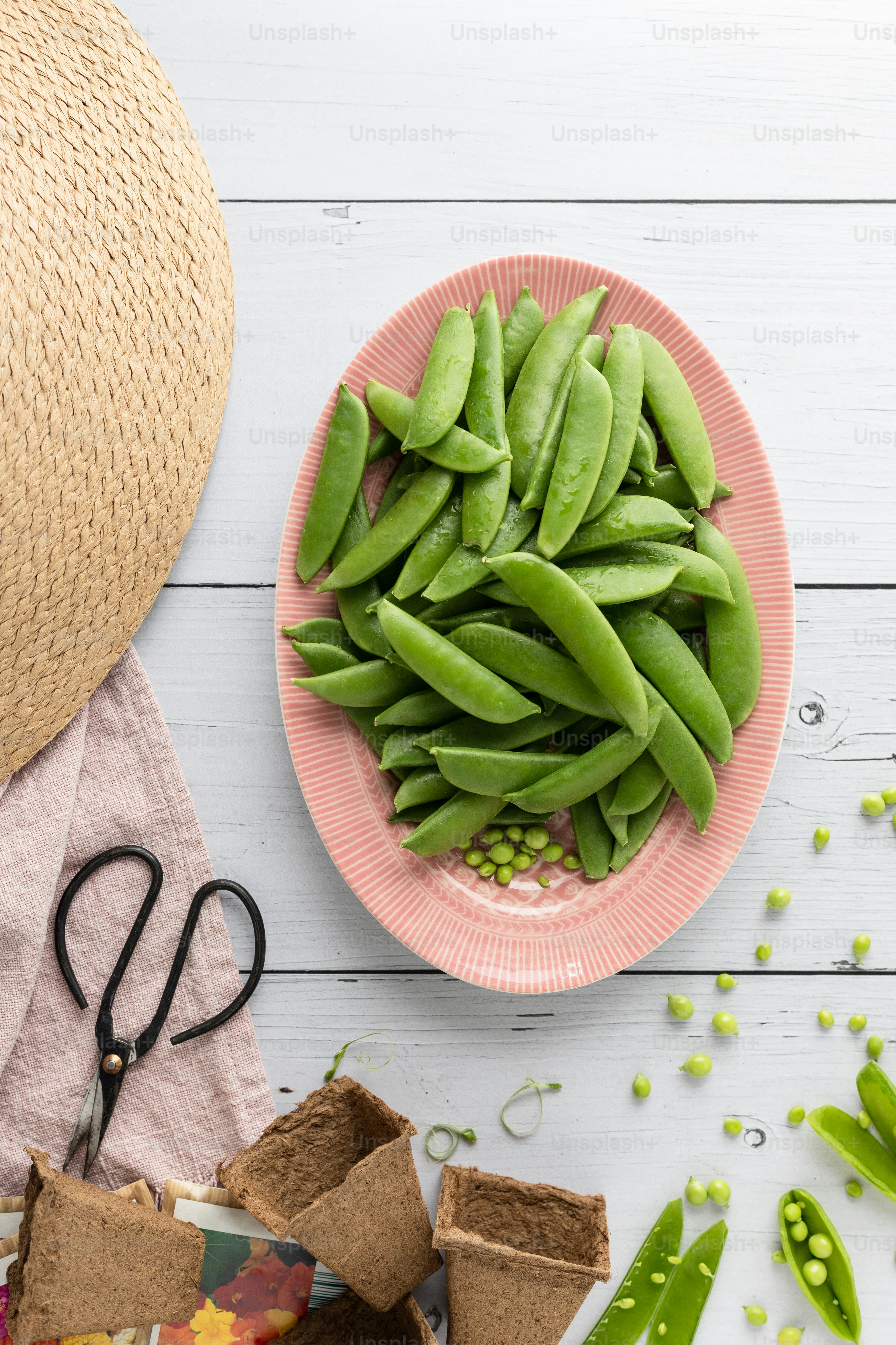 une assiette de haricots verts à côté d’un bol de pois