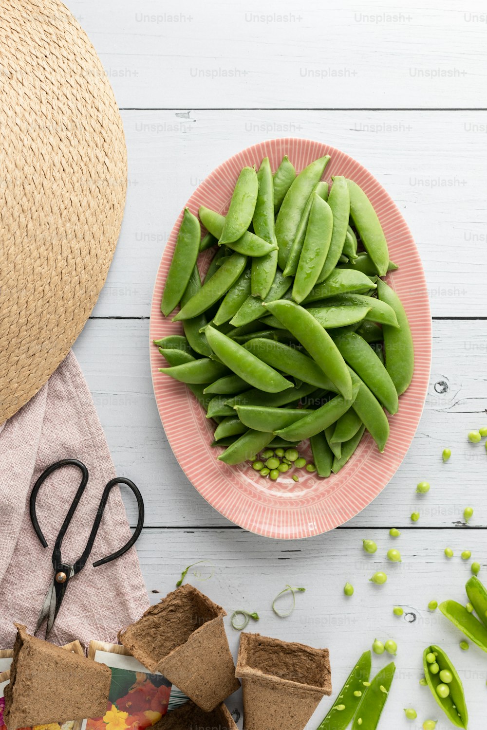 a plate of green beans next to a bowl of peas