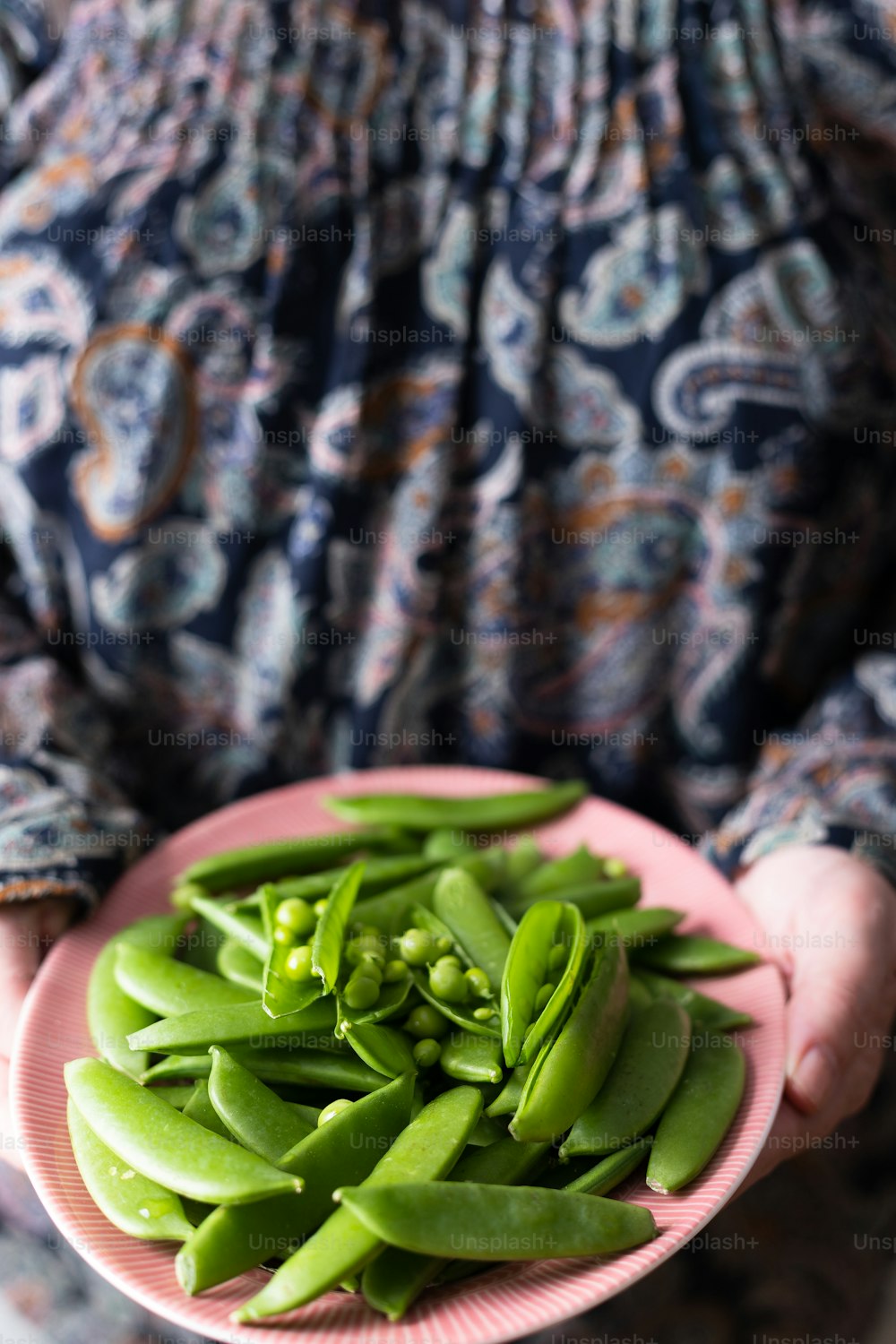 a person holding a plate of green beans