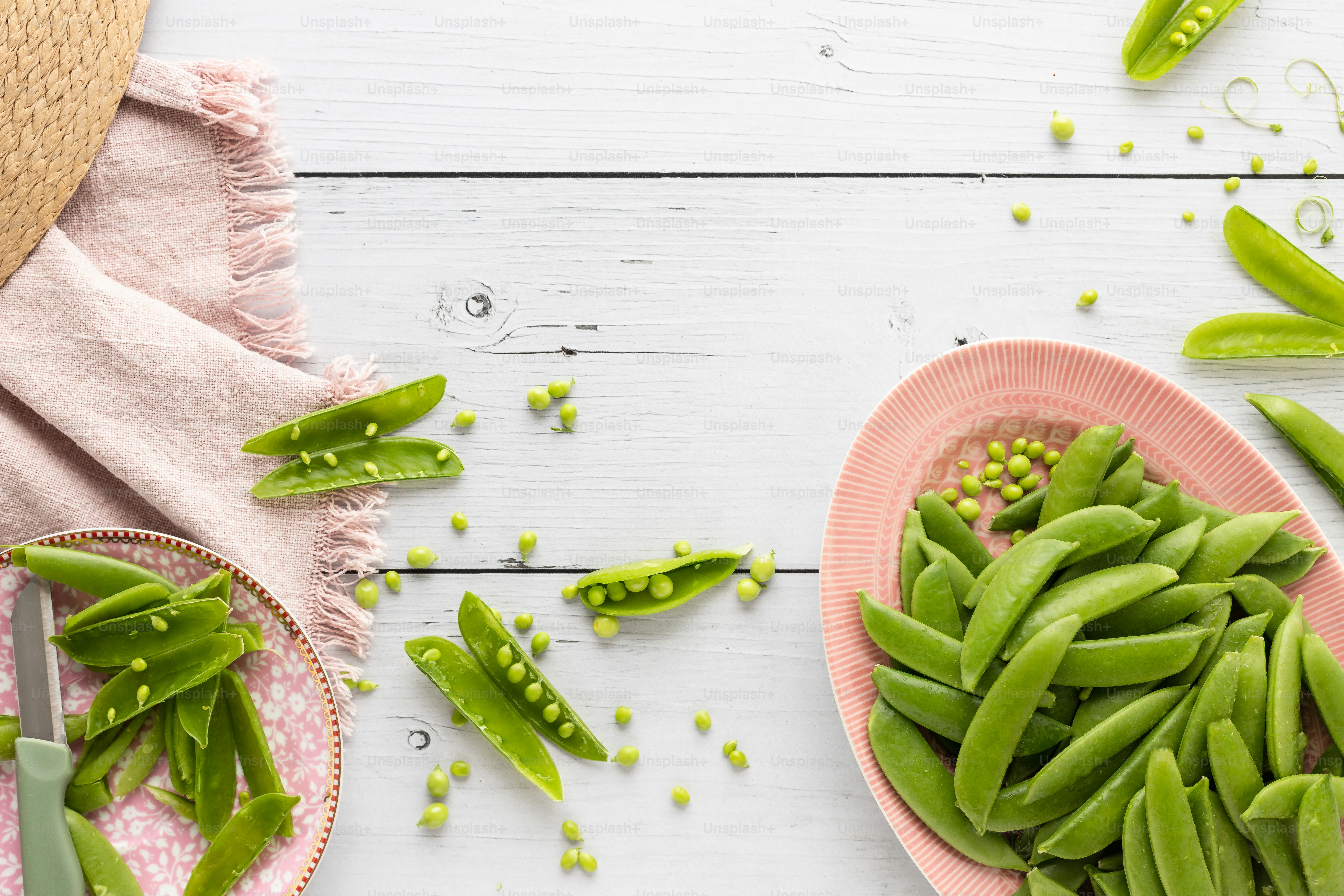 a plate of green beans next to a bowl of peas