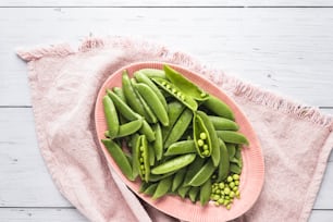 a plate of green beans and peas on a pink plate