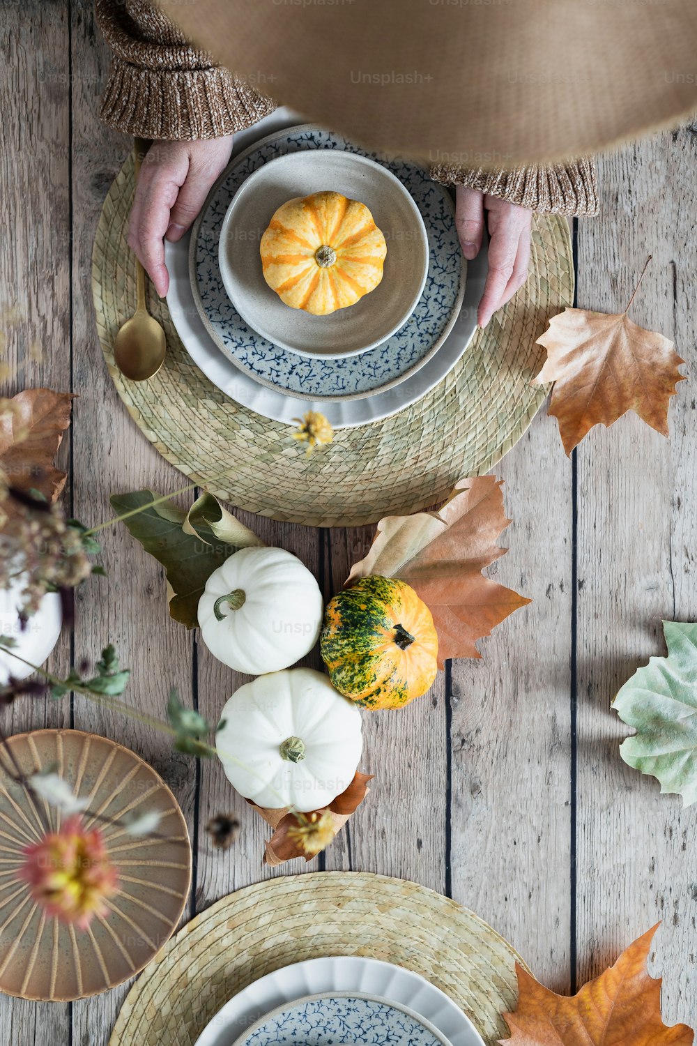 a table topped with plates and bowls filled with pumpkins