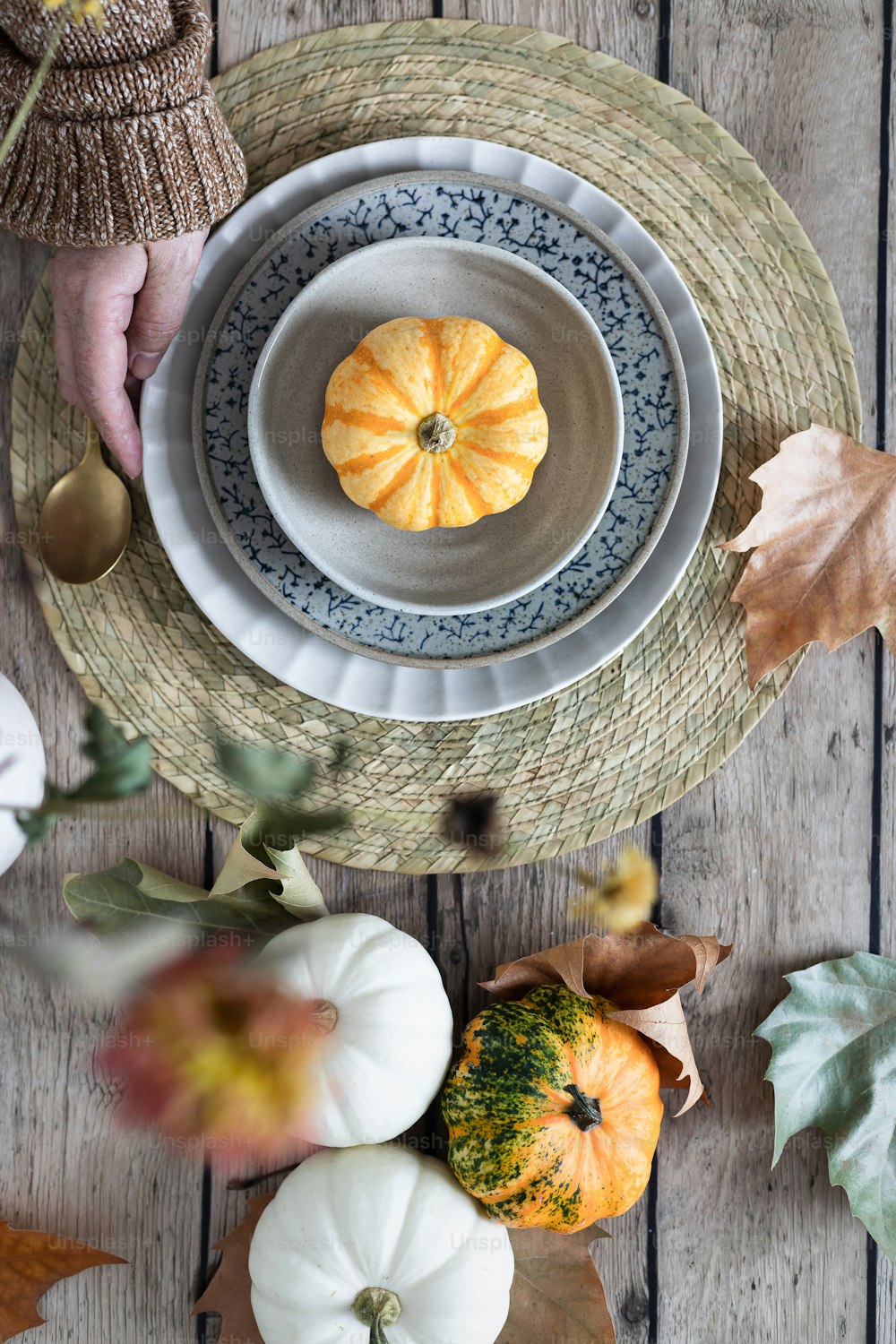 a table topped with plates and pumpkins on top of a wooden table