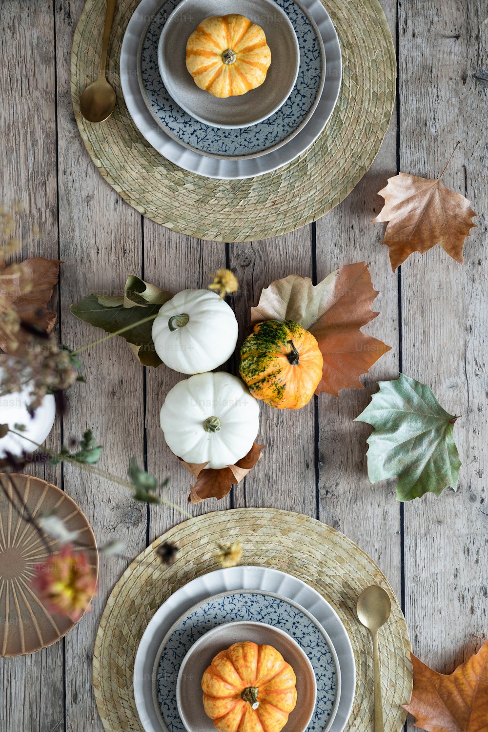 a wooden table topped with plates and bowls filled with pumpkins