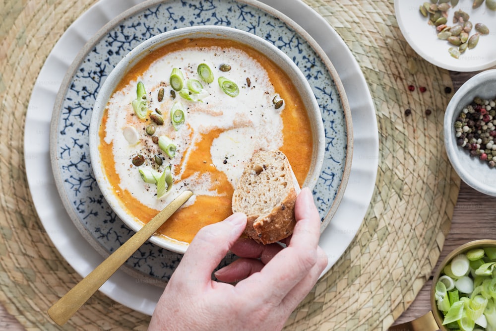 a person holding a spoon in a bowl of soup