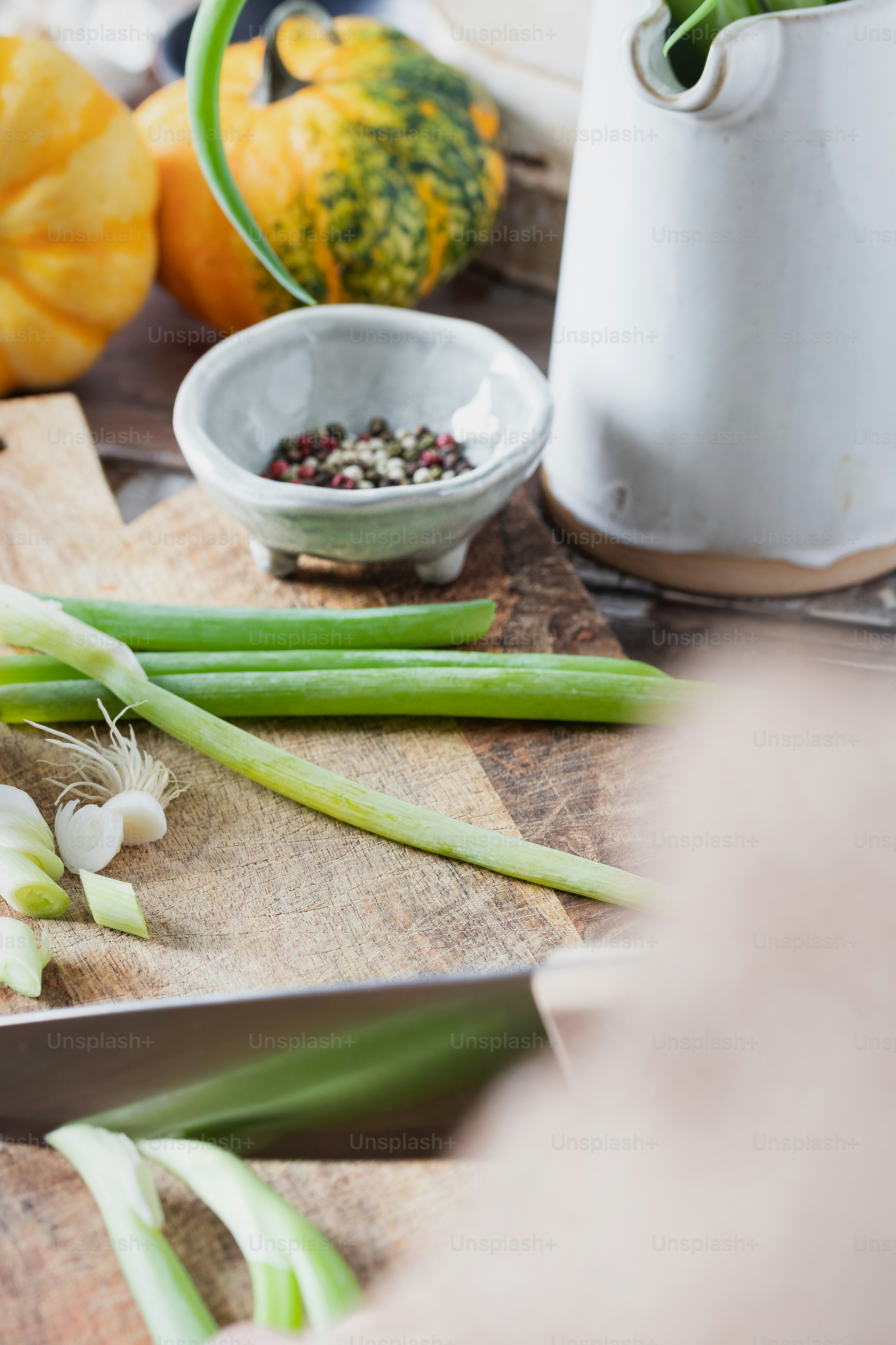 A cutting board topped with green onions and onions photo Peppercorns
