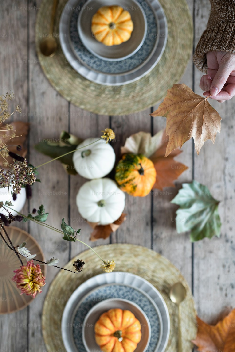 a wooden table topped with plates and bowls filled with pumpkins