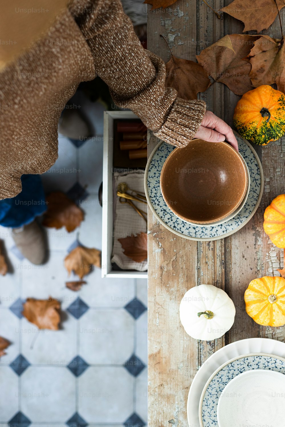 Una persona sosteniendo una taza de café encima de una mesa de madera