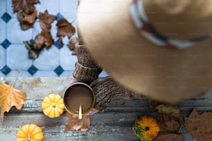 a person holding a cup of coffee in front of fall leaves
