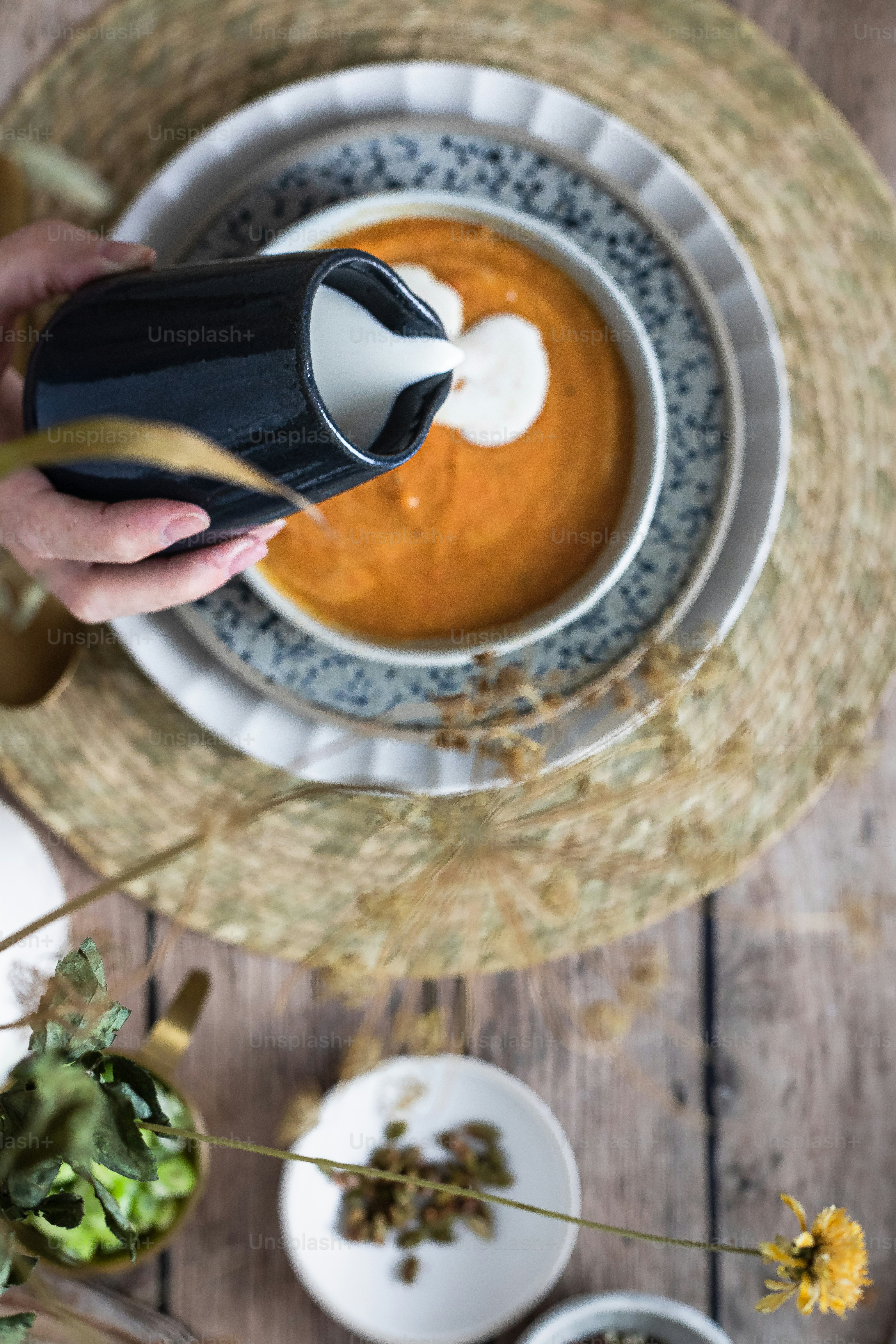 a person pouring a beverage into a bowl of soup