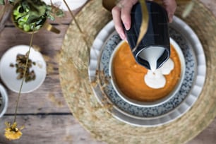 a person pouring cream over a bowl of food