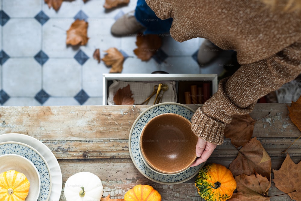 a woman putting a cup of coffee on top of a wooden table