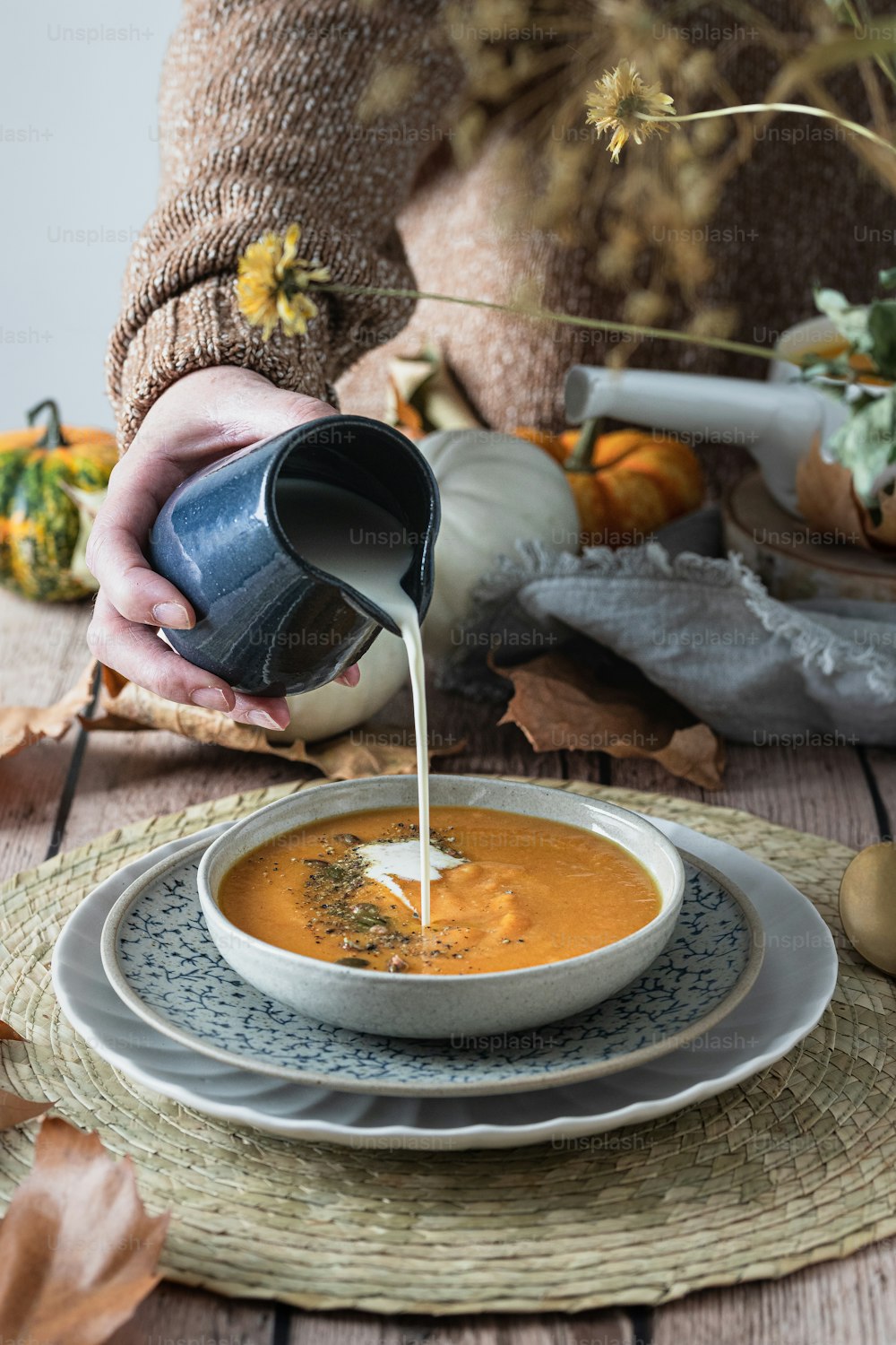 une personne verse du lait dans un bol de soupe