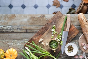 una tabla de cortar de madera cubierta con verduras junto a un cuchillo