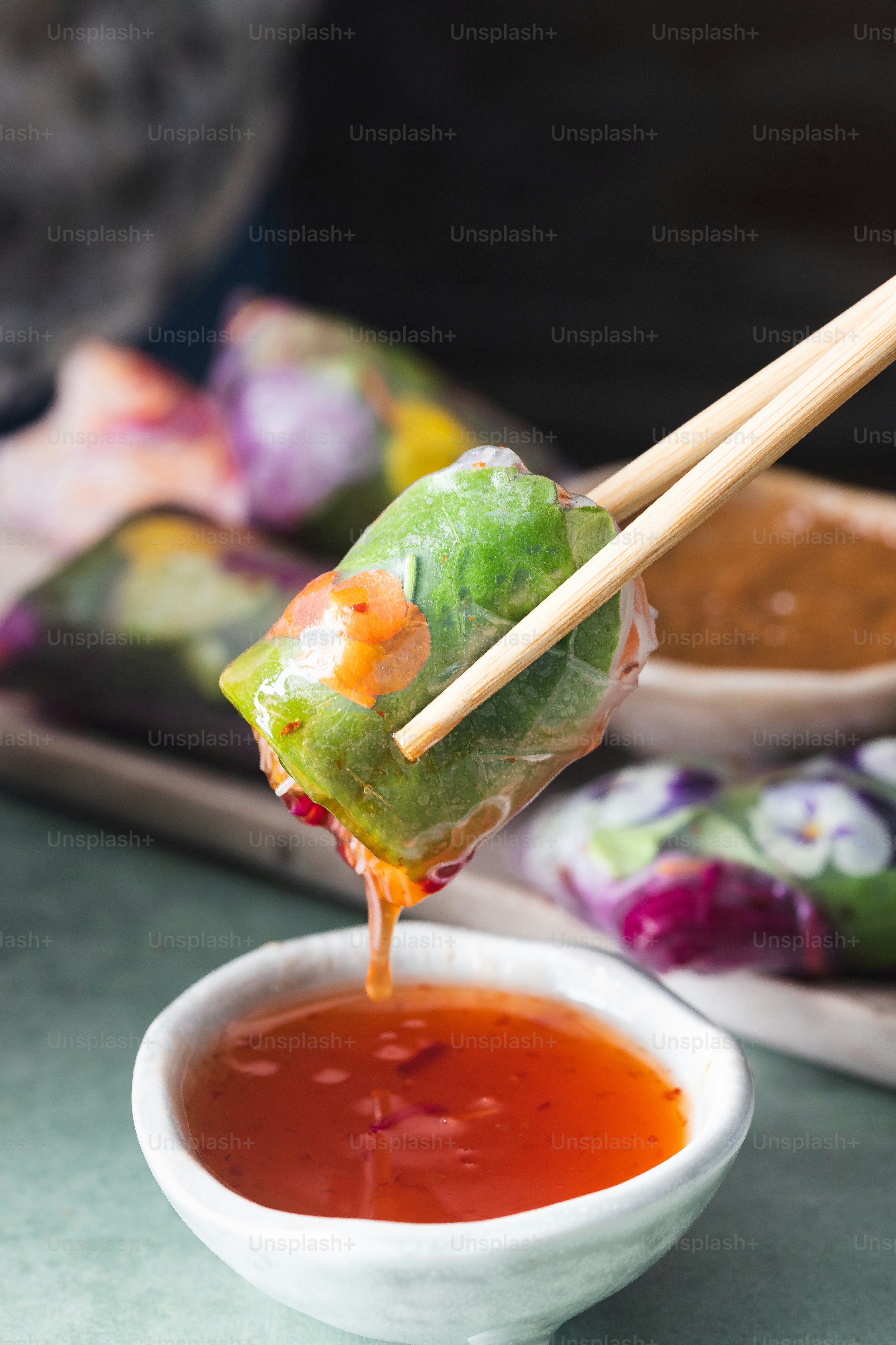 a person dipping sauce into a bowl with chopsticks
