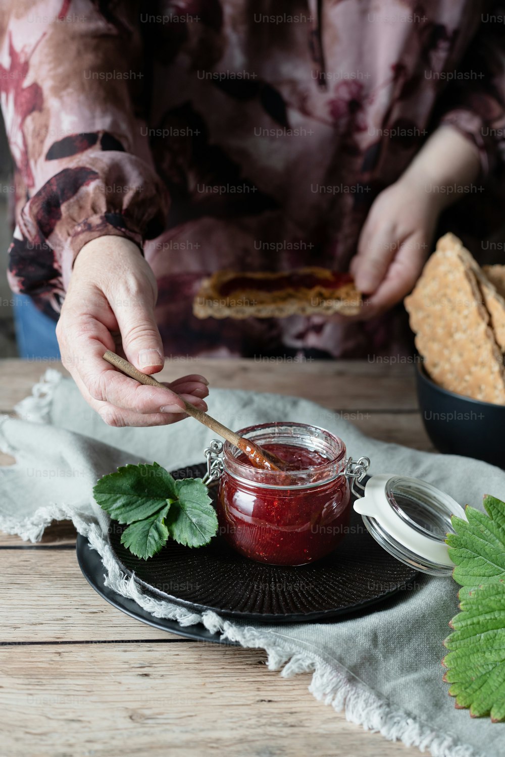 a person holding a spoon over a jar of jam