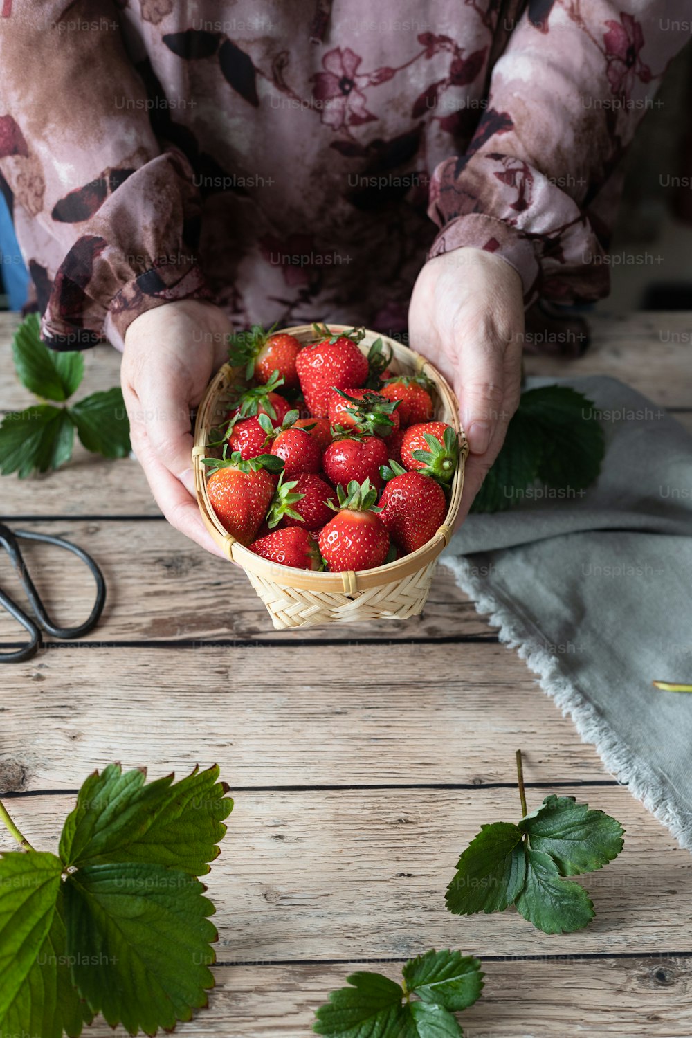 a person holding a basket of strawberries on a table