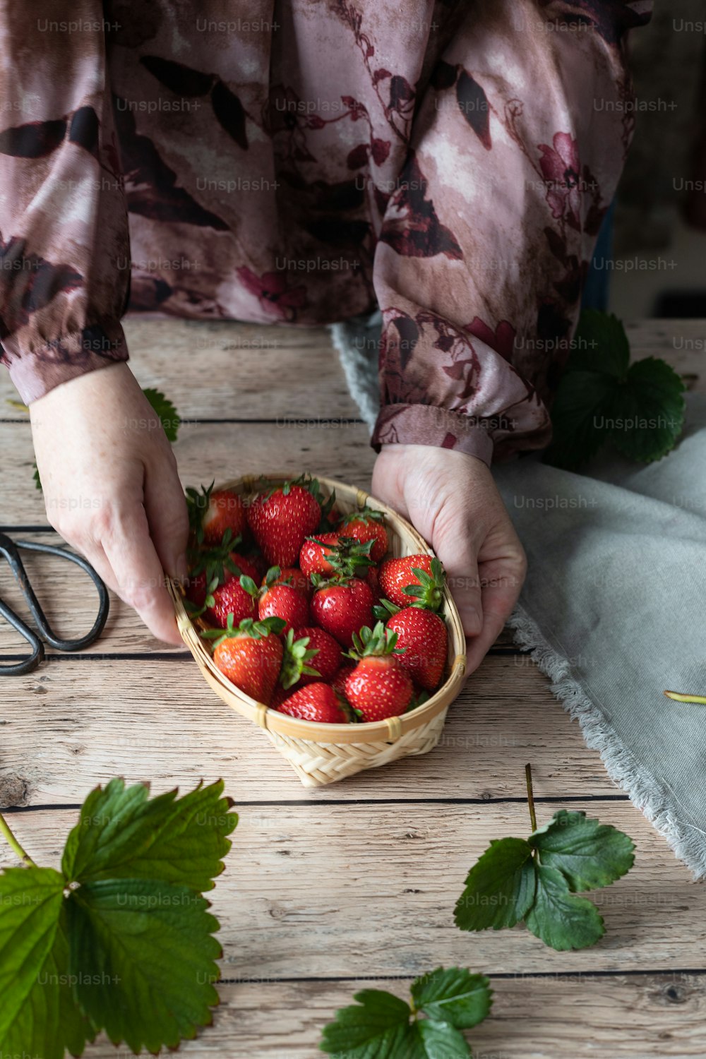 a person holding a basket of strawberries on a table