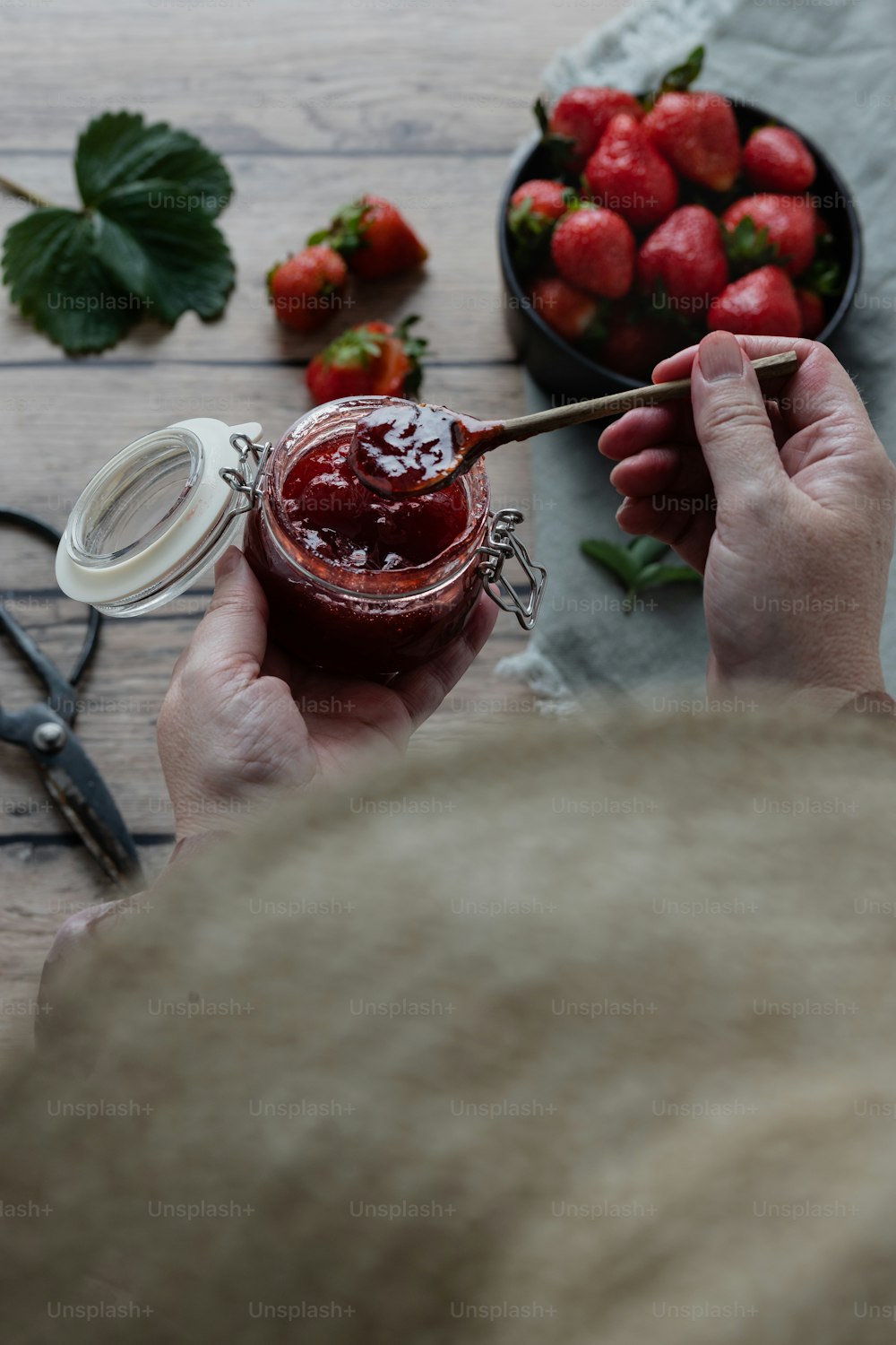 a person holding a jar of strawberry jam