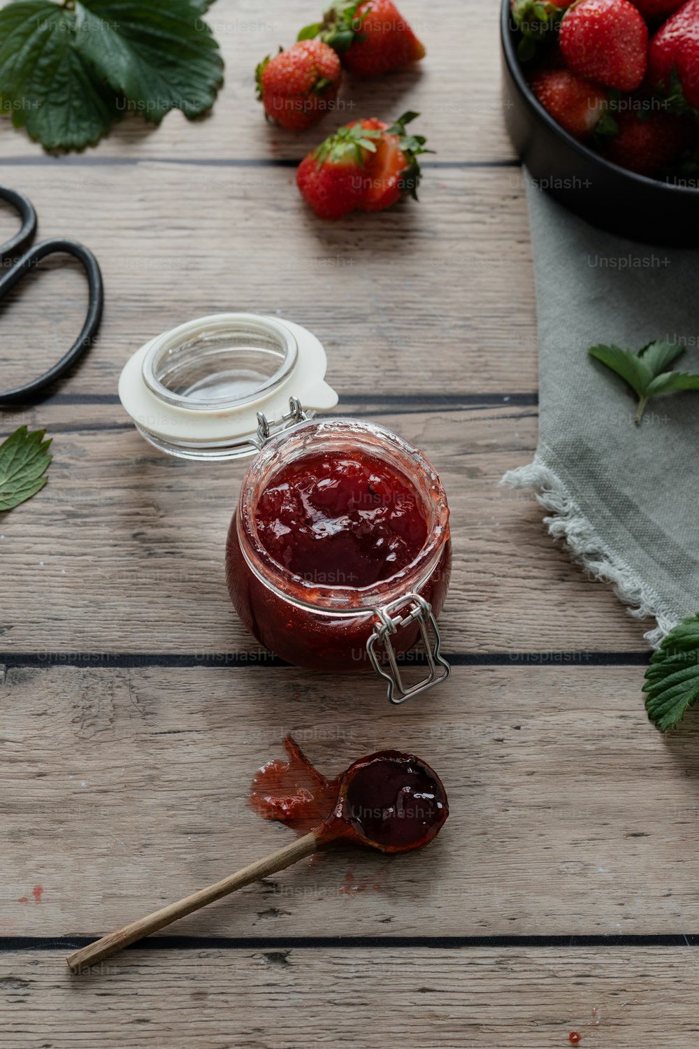 a jar of strawberry jam next to a bowl of strawberries