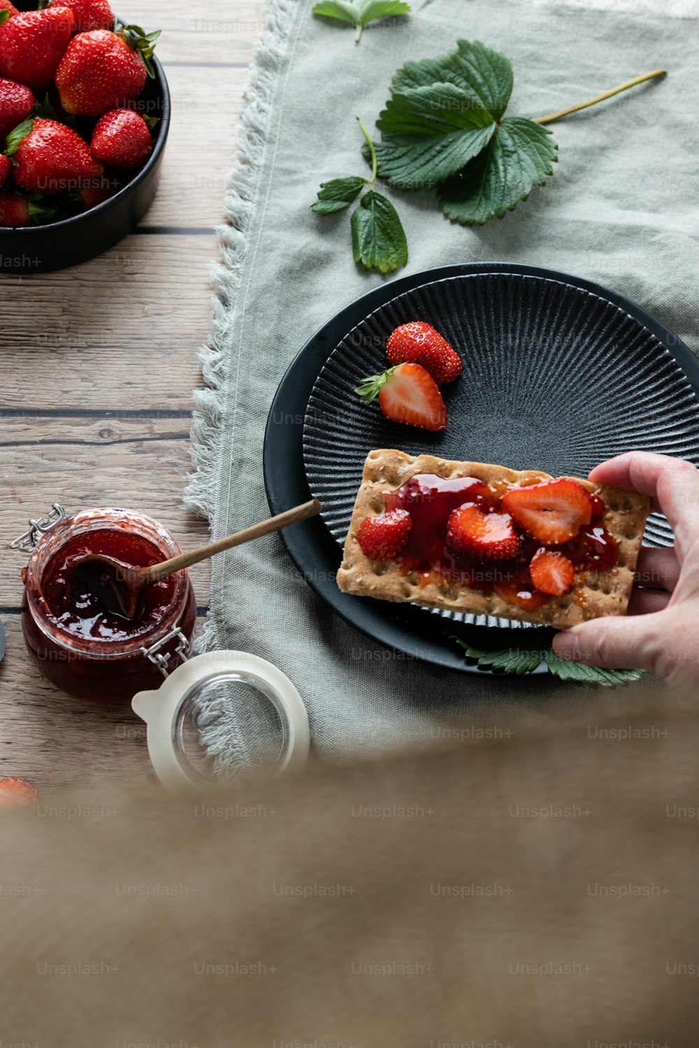a person holding a piece of waffle with strawberries on it