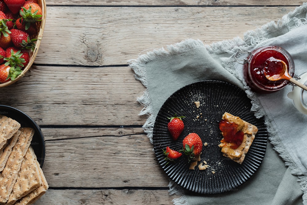 a plate of strawberries next to a bowl of strawberries