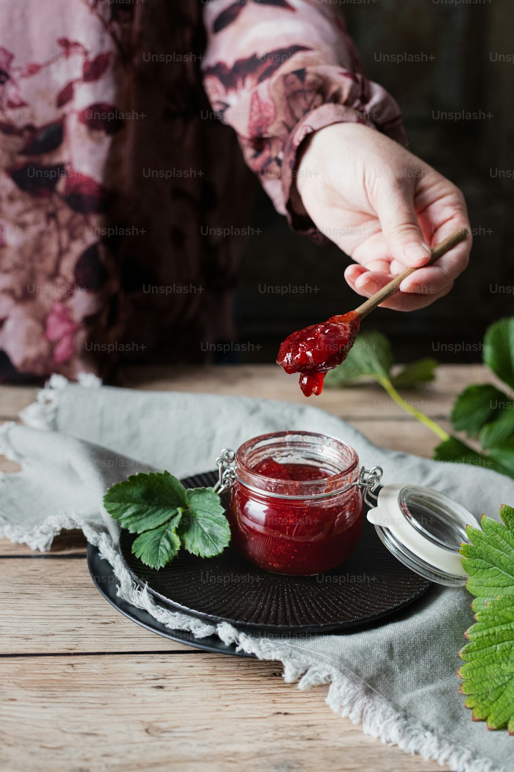 a person holding a spoon with a jar of jam on it