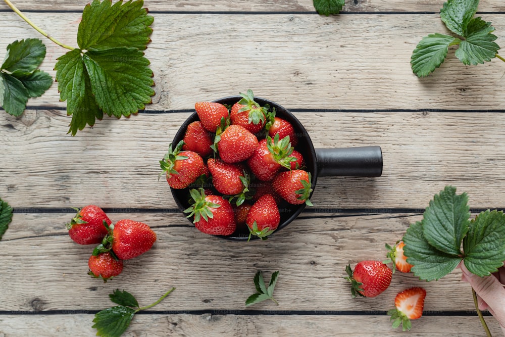 a bowl of strawberries on a wooden table