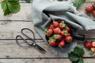 a bowl full of strawberries next to a pair of scissors
