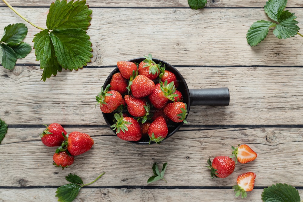 a bowl of strawberries on a wooden table