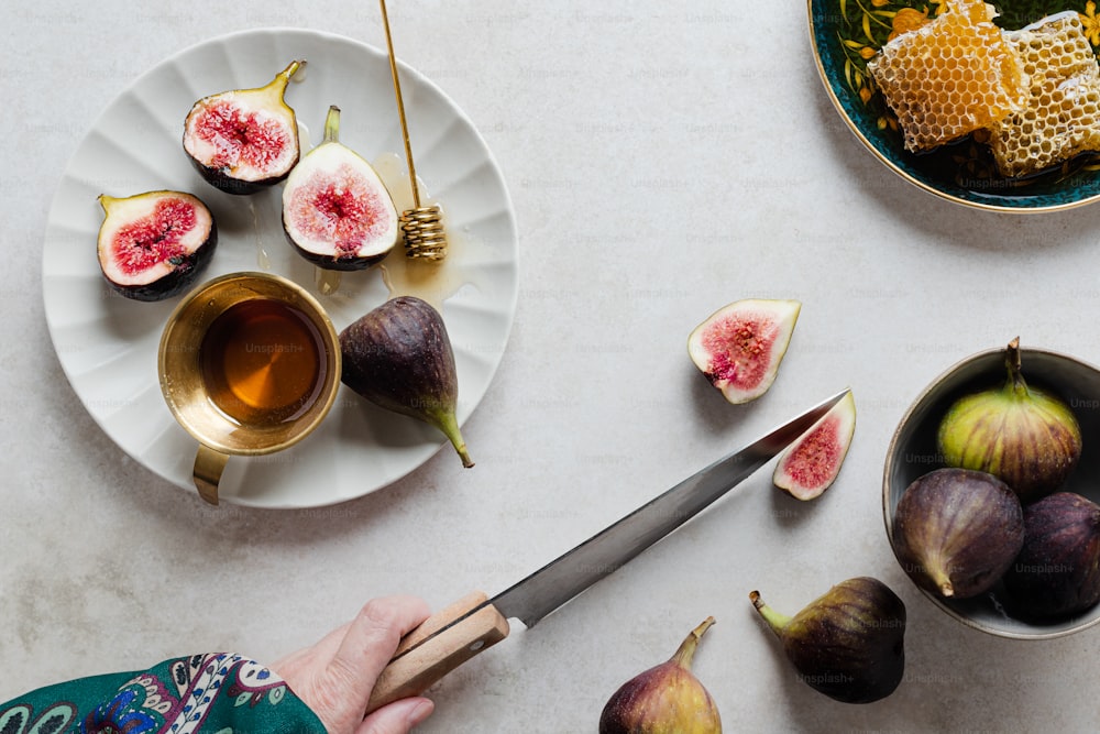 a person cutting figs on a plate with a knife
