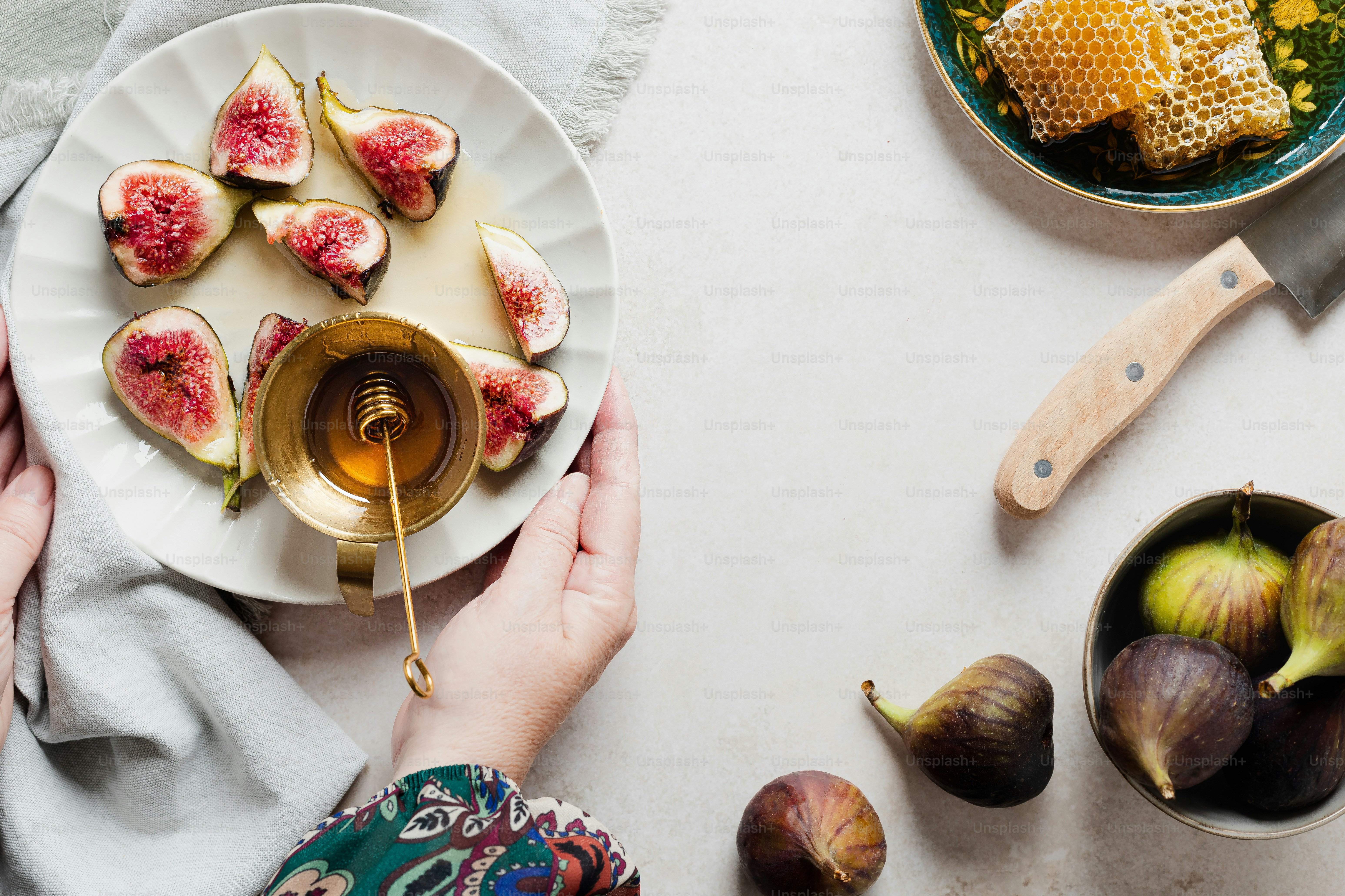 a person holding a plate with figs and honey on it