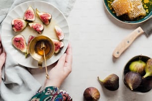 a person holding a plate with figs and honey on it