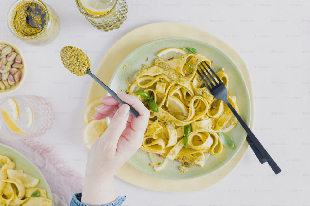 a person holding a fork over a plate of pasta