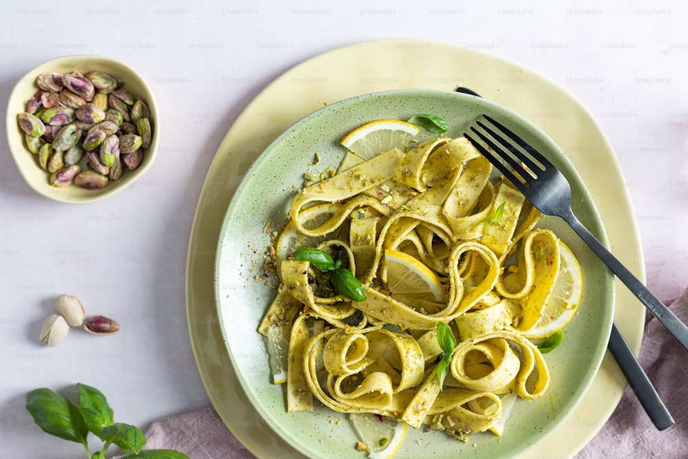 a plate of pasta with a fork and a bowl of nuts