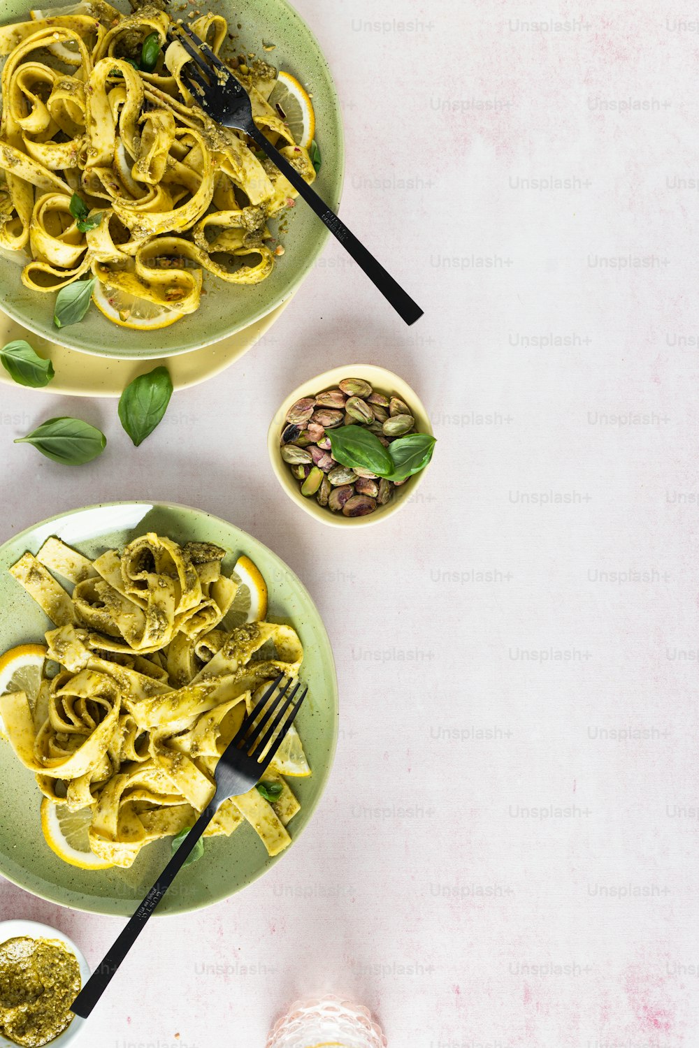 two plates of pasta with pesto on the side