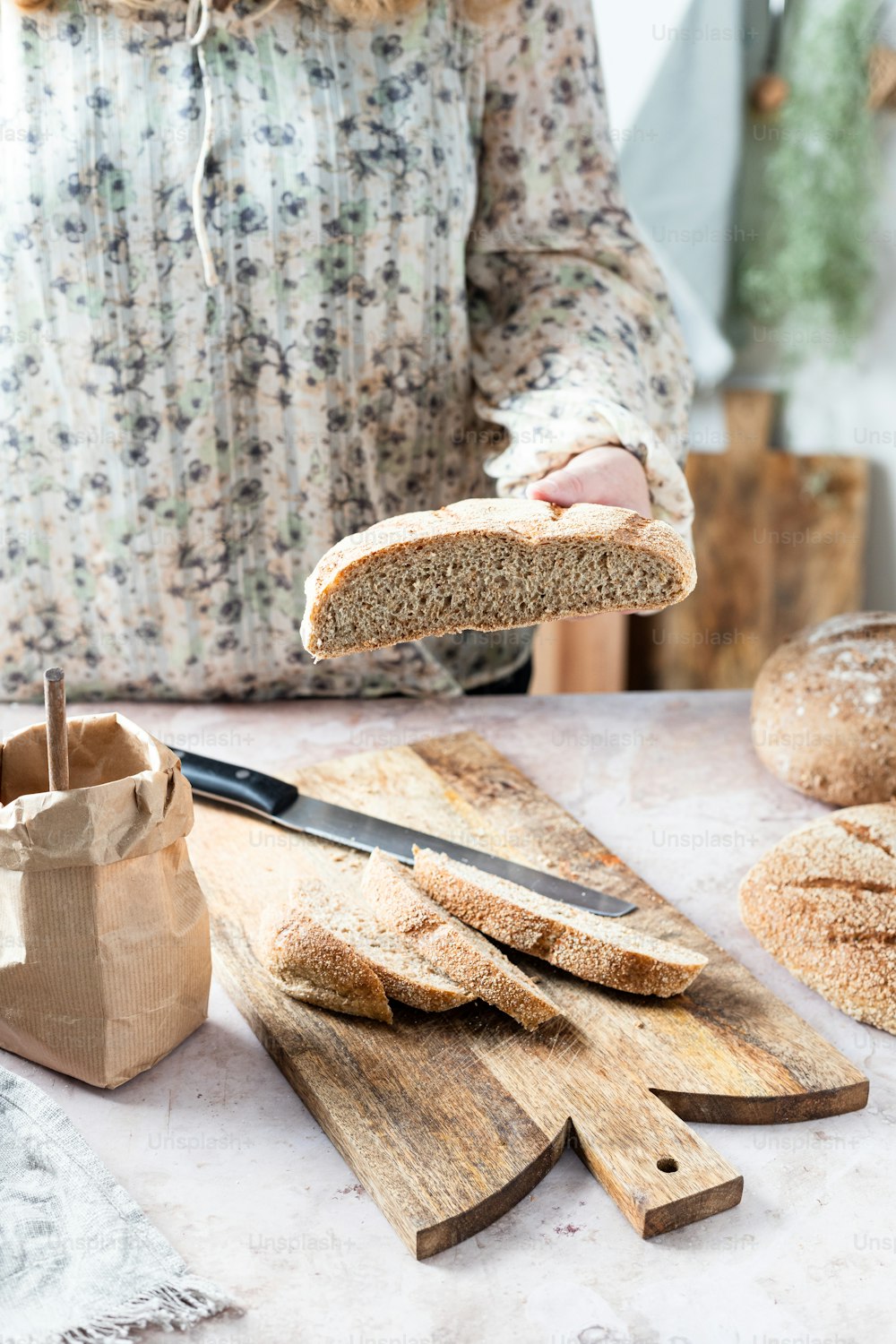 a woman holding a piece of bread over a cutting board