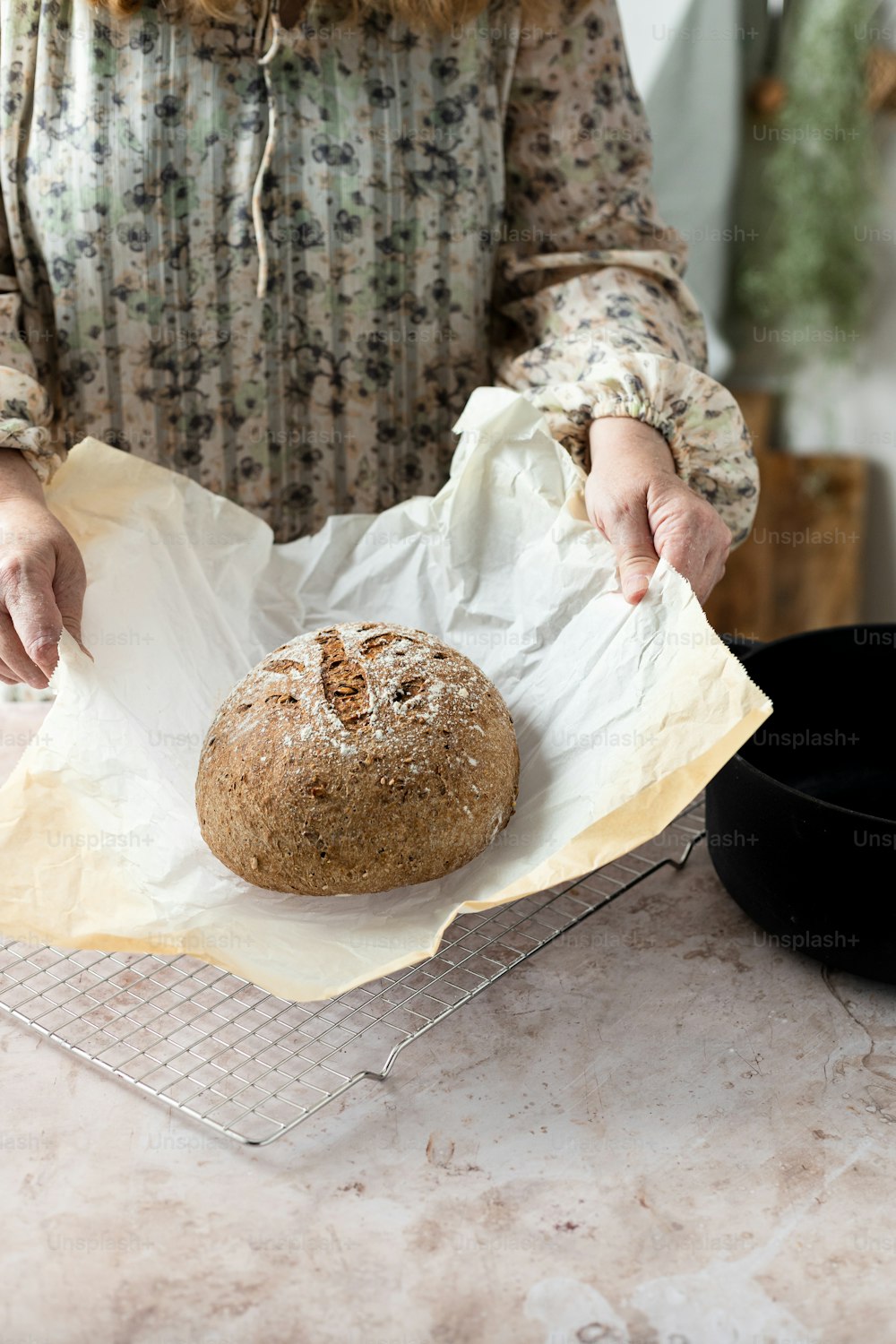 a woman holding a loaf of bread on top of a table