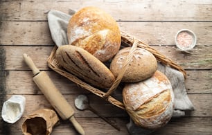 uma cesta cheia de pães em cima de uma mesa de madeira