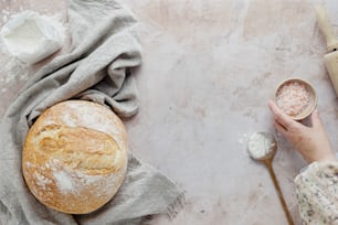 a person holding a bowl of food next to a loaf of bread