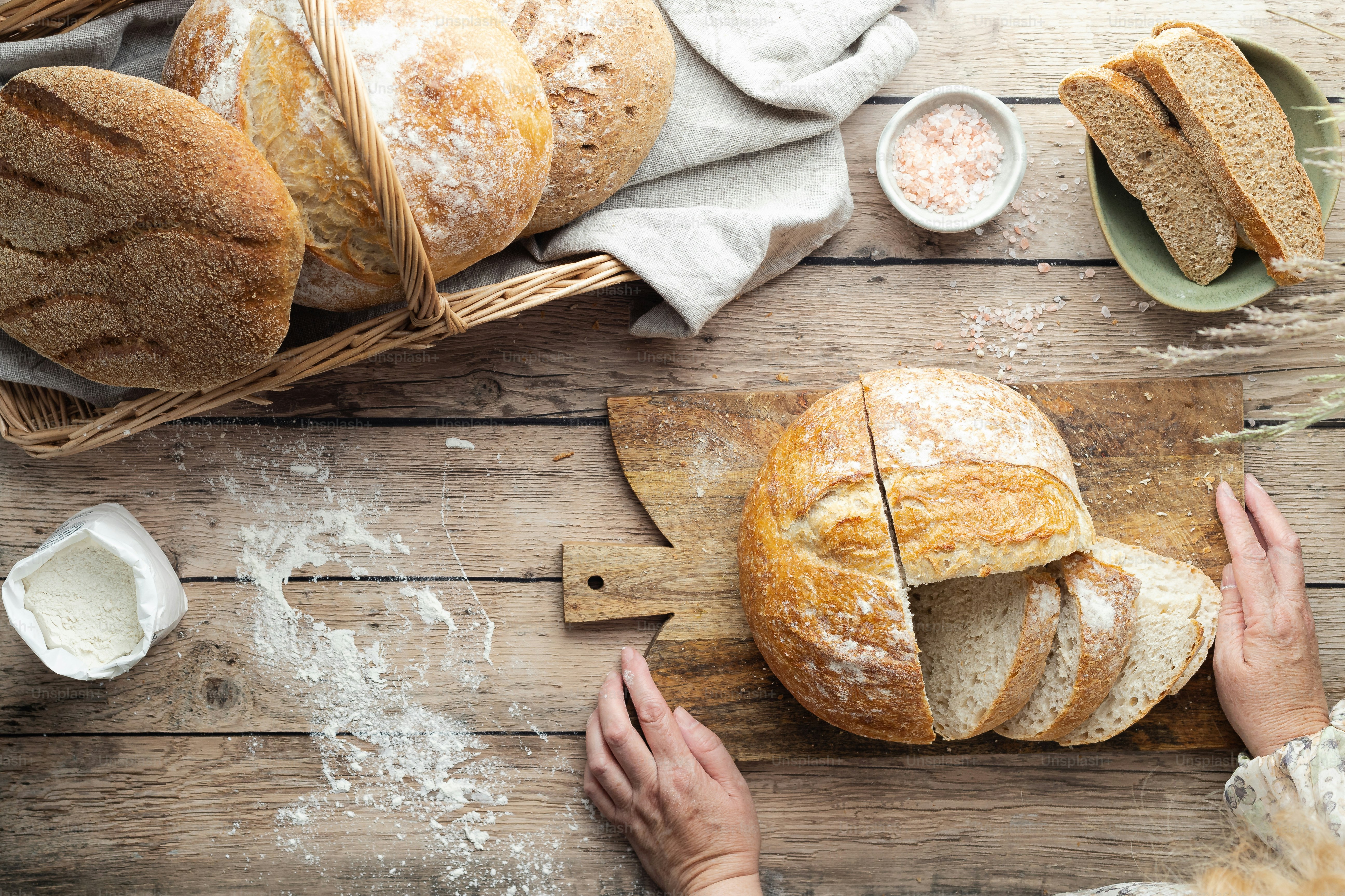 a person cutting a loaf of bread on a cutting board