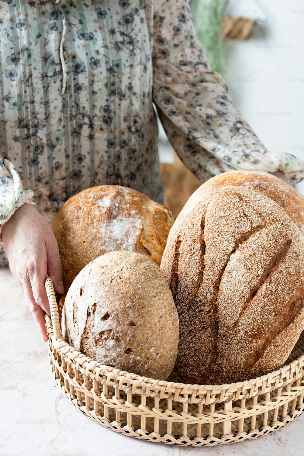 a woman holding a basket of bread and loaves