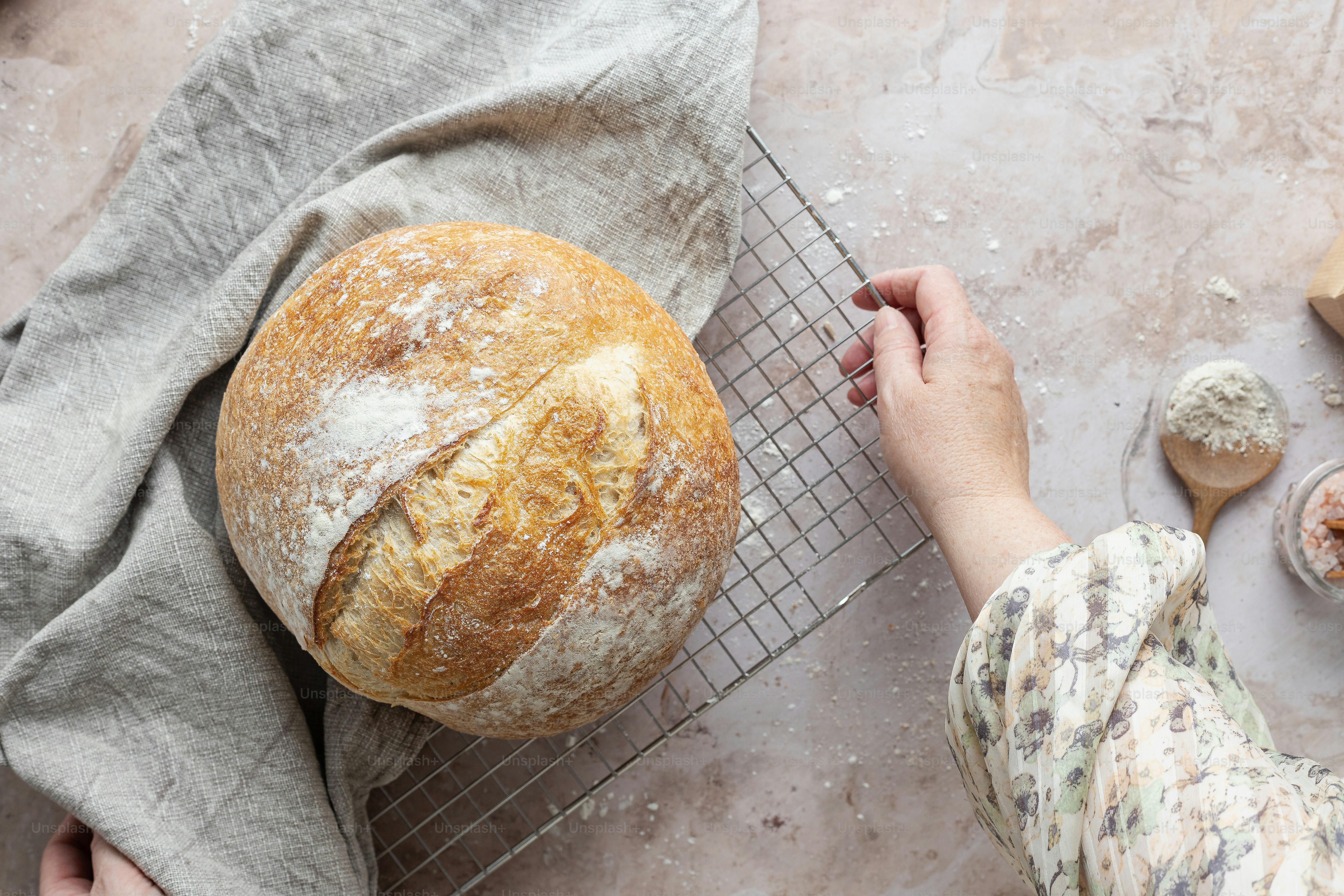 a person holding a loaf of bread on a cooling rack