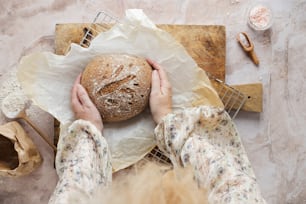uma pessoa segurando um pão em cima de uma mesa