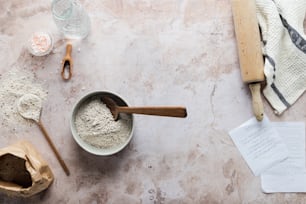 a bowl of flour next to a wooden spoon