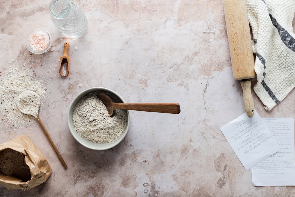 a bowl of flour next to a wooden spoon