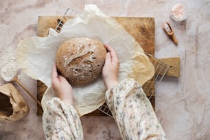 a person holding a loaf of bread on top of a table