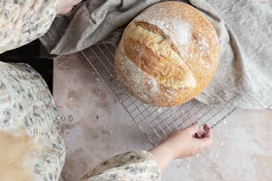 a person holding a loaf of bread on a cooling rack