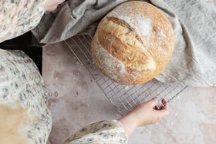 uma pessoa segurando um pão em uma prateleira de resfriamento