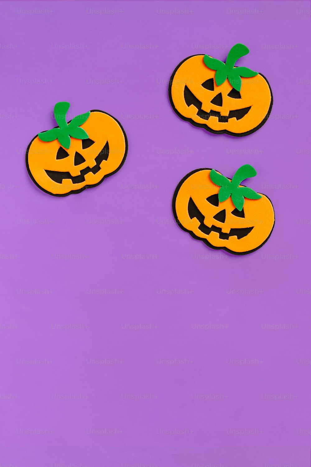 three orange pumpkins on a purple background